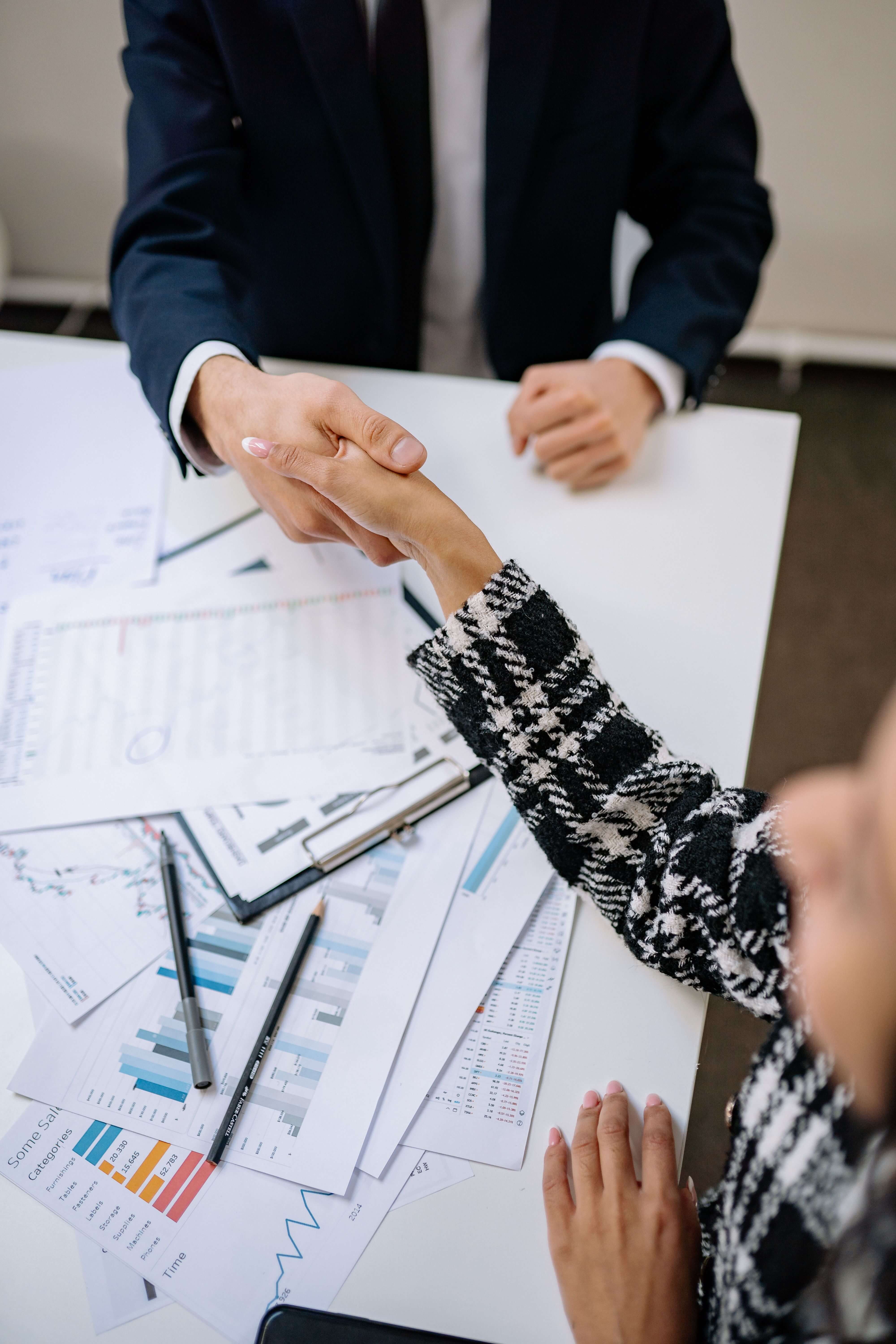L'audit patrimonial global — poignée de main au-dessus de graphiques financiers